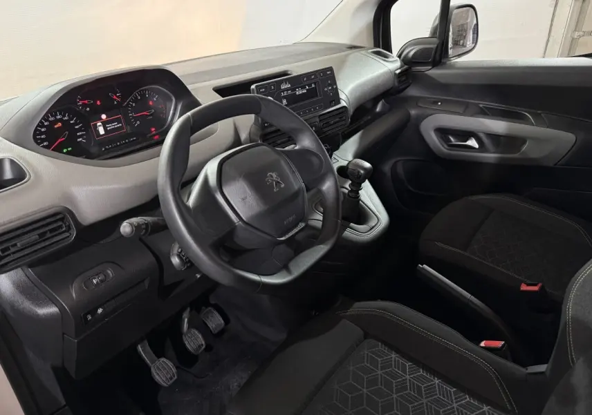 Vue intérieure côté conducteur du Peugeot Rifter 2019, tableau de bord noir avec volant compact et levier de vitesse manuel.