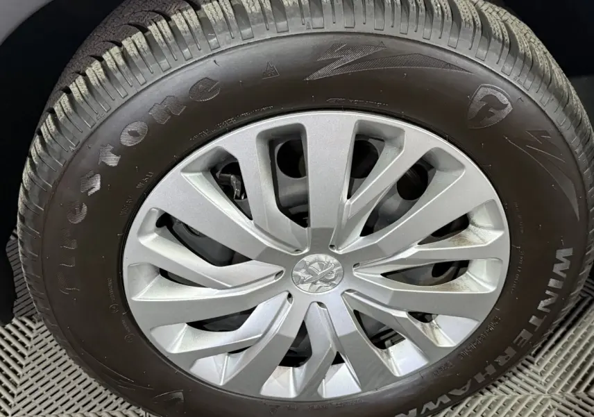 Gros plan sur la roue avant droite du Peugeot Rifter blanc, mettant en valeur la jante argentée et le pneu Firestone.