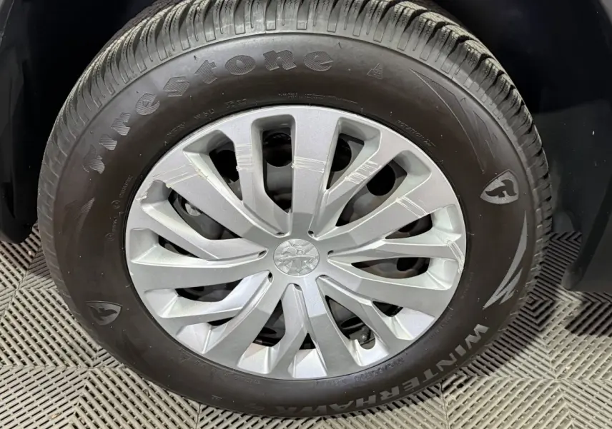 Gros plan sur la roue avant droite du Peugeot Rifter blanc avec jante en alliage et pneu Firestone Winterhawk.