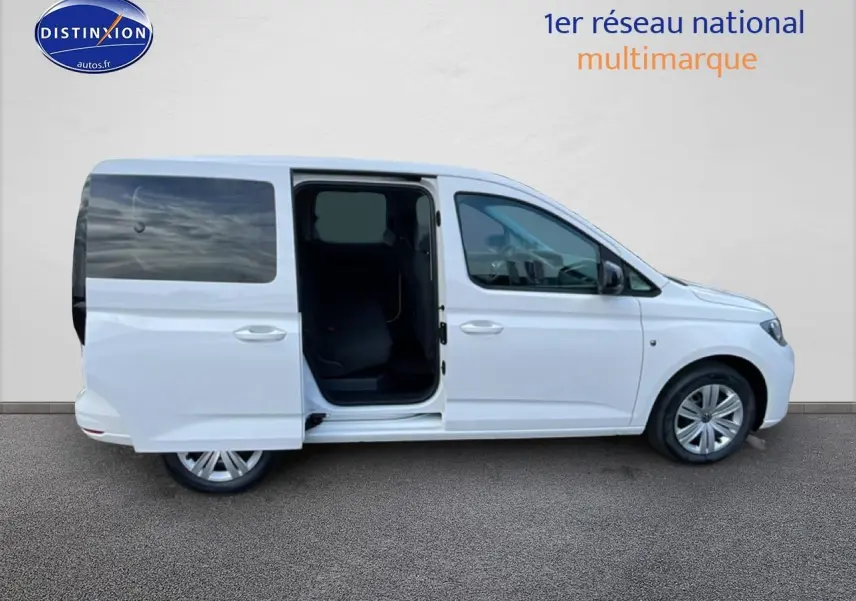 Vue de profil droit d'un Volkswagen Caddy blanc 2025 avec porte coulissante arrière ouverte sur fond neutre.