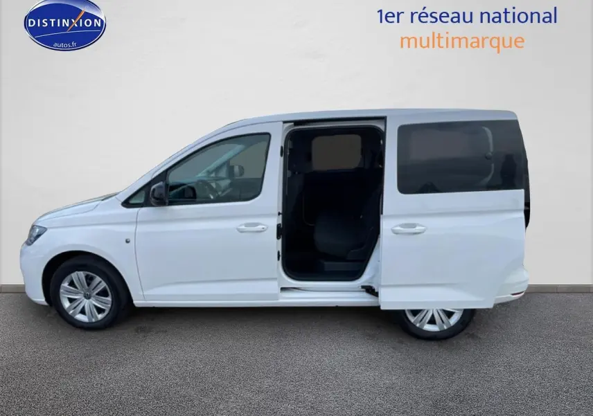 Vue de profil côté gauche d'un Volkswagen Caddy blanc 2025 avec porte coulissante arrière ouverte.
