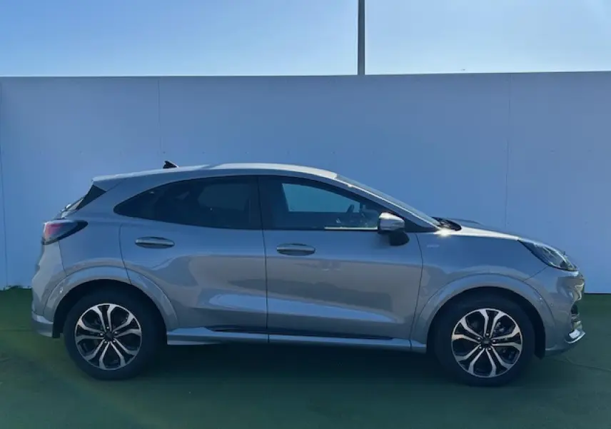 Profil droit du Ford Puma gris Solar 2023 avec jantes alliage et vitres surteintées, sur fond neutre.