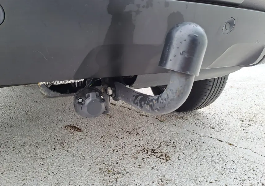 Gros plan sur l'attelage arrière gris urbain du Dacia Duster 2024 avec prise électrique sous le pare-chocs.