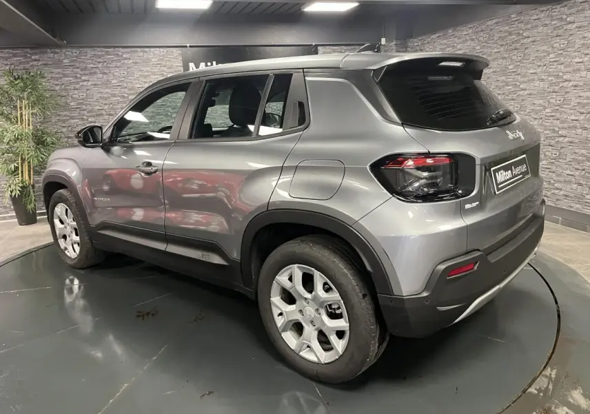 Vue 3/4 arrière droite du Jeep Avenger gris métallisé avec jantes alliage et coques de rétroviseurs noires.