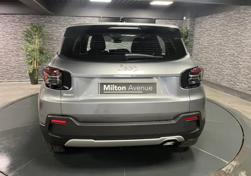 Vue arrière du Jeep Avenger gris métallisé avec feux arrière noirs et logo Jeep visible en intérieur.
