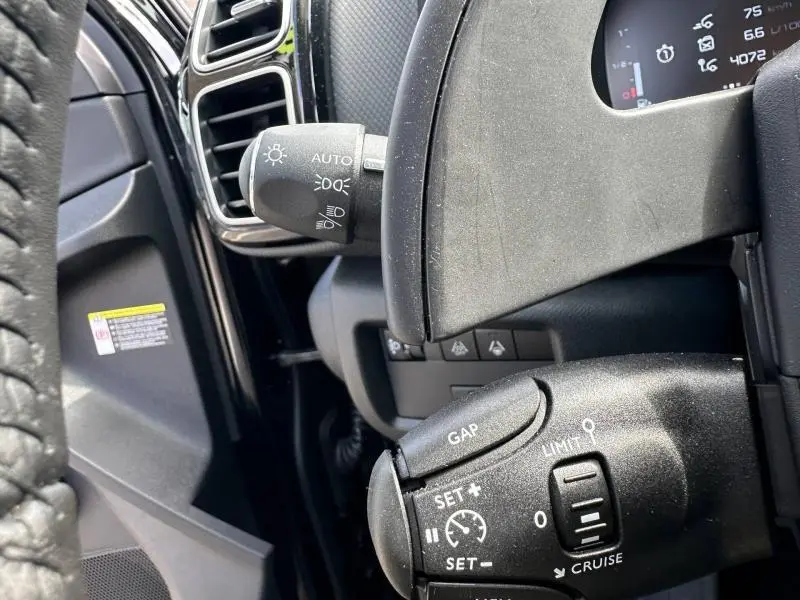 Gros plan sur les commandes au volant du Citroën C5 Aircross noir Perla Nera, mettant en valeur les réglages du régulateur de vitesse.