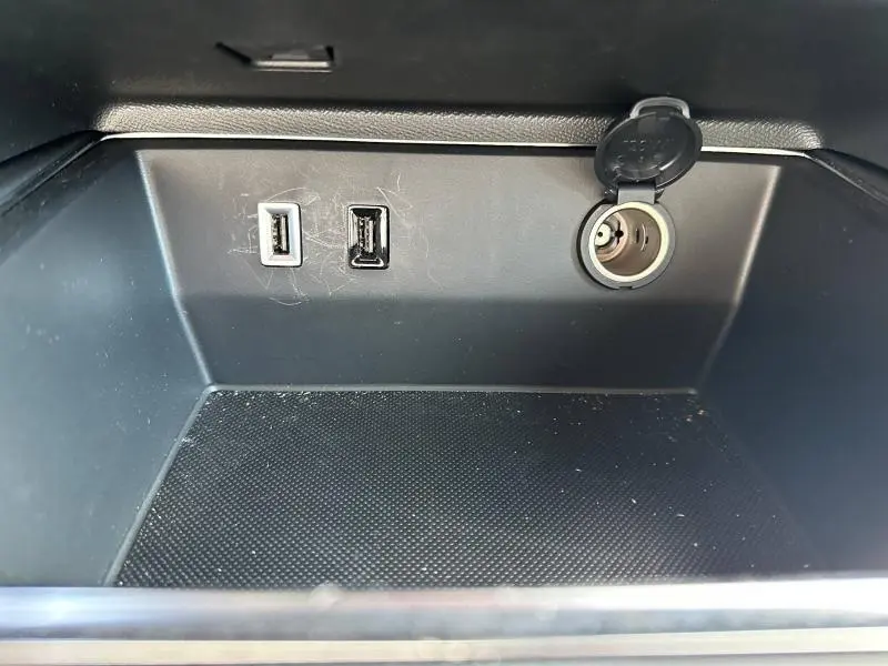 Gros plan sur la console centrale noire du Citroën C5 Aircross 2025, montrant deux ports USB et une prise 12V ouverte.