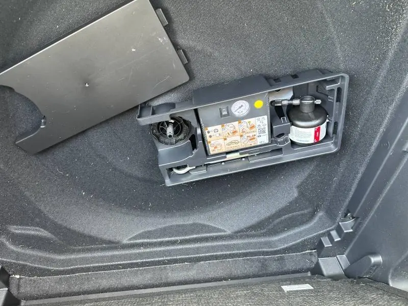 Détail du compresseur de pneu intégré dans le coffre du Citroën C5 Aircross 2025 noir Perla Nera, vue intérieure.