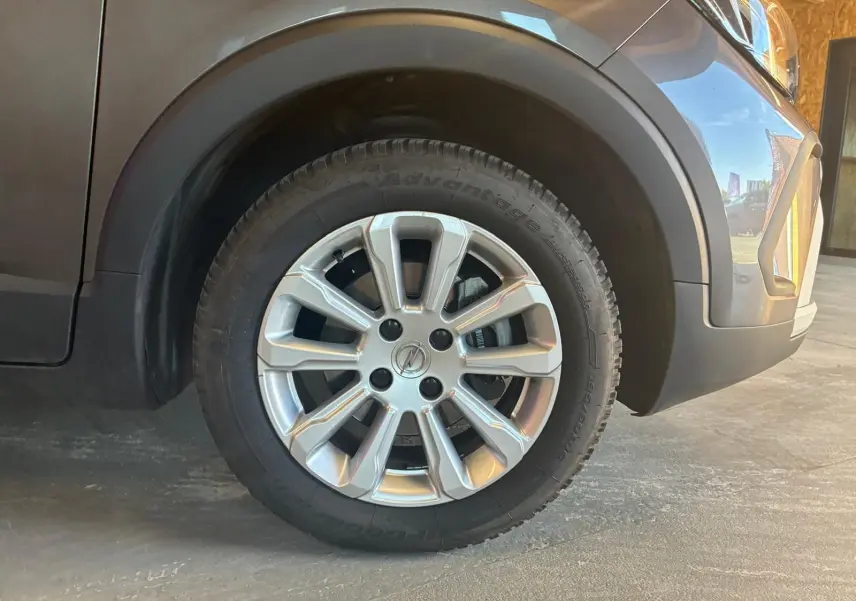 Gros plan sur la roue avant droite gris argenté d’un Opel Crossland gris, avec jante alu et partie avant du véhicule visible.