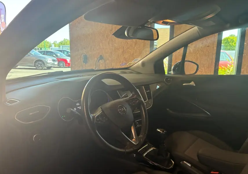 Vue intérieure côté conducteur de l'Opel Crossland gris, montrant le volant multifonction et la console centrale avec boîte manuelle.