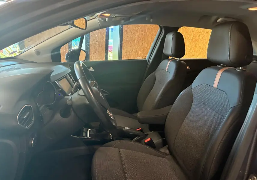 Vue intérieure côté conducteur de l’Opel Crossland gris, mettant en valeur les sièges tissu gris-noir avec bande centrale marron.