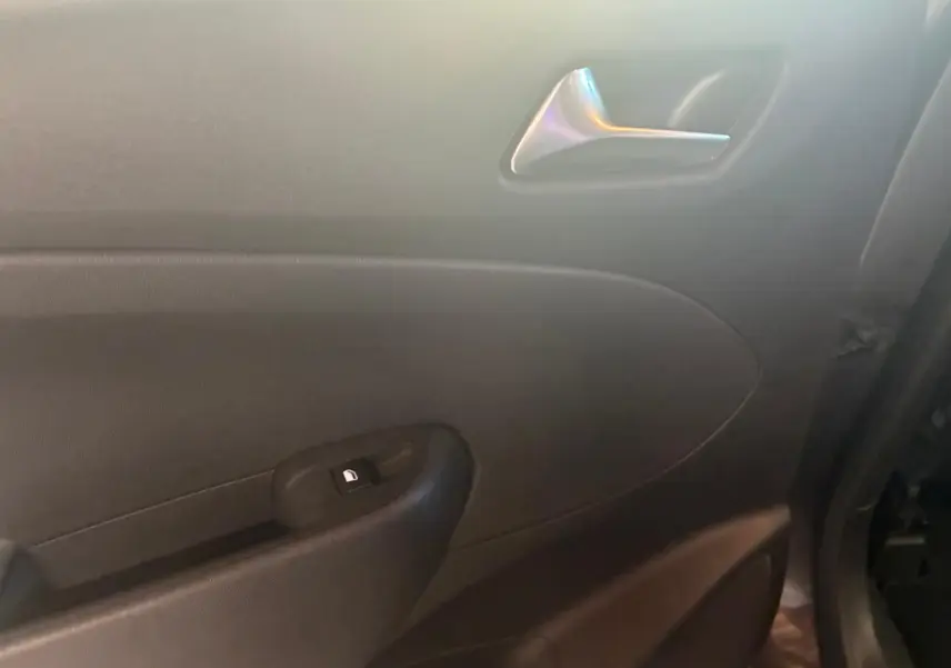 Gros plan sur la porte intérieure côté droit de l’Opel Crossland gris, montrant la poignée argentée et le bouton de verrouillage.