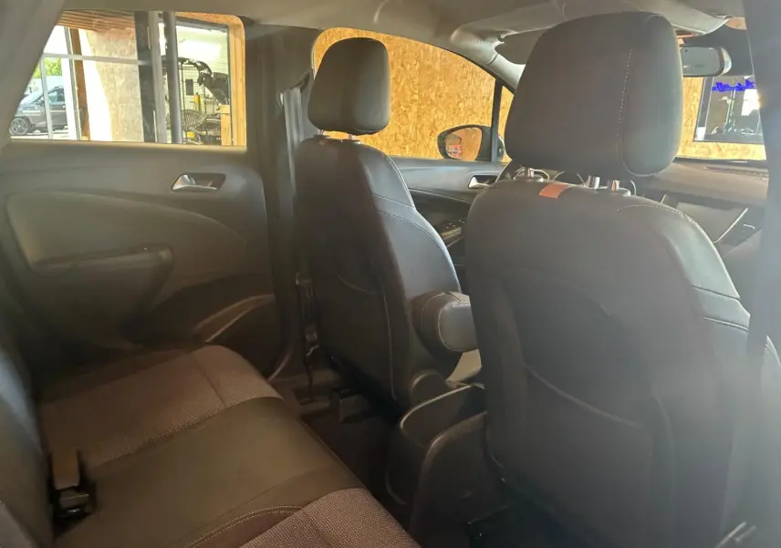 Vue intérieure arrière de l’Opel Crossland 2021, sièges tissu gris et noir avec appuie-bras central déployé.