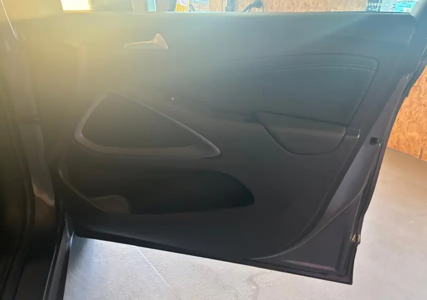 Vue intérieure de la porte arrière droite d'une Opel Crossland gris, avec poignée et panneau en tissu noir.