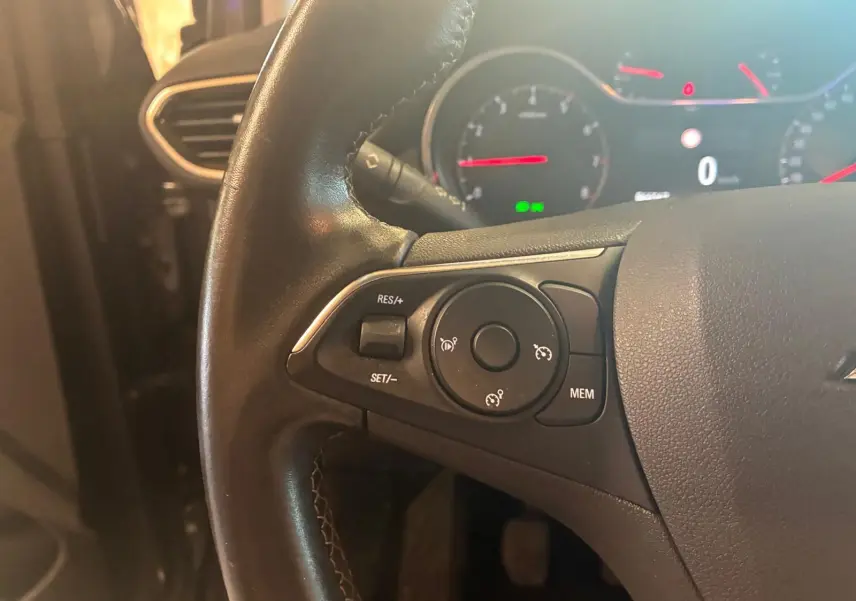 Gros plan sur le volant noir de l'Opel Crossland 2021, montrant les commandes de régulateur de vitesse à gauche.