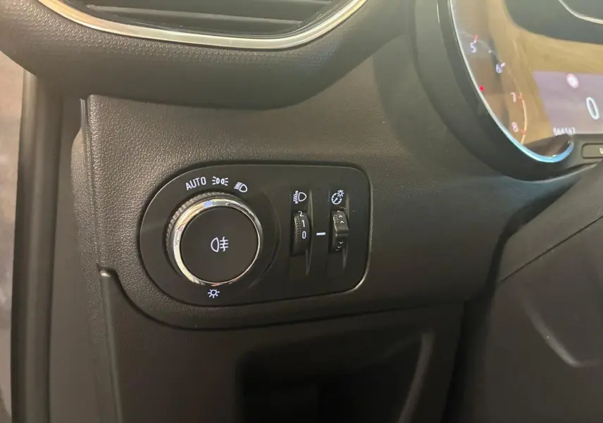 Gros plan sur le panneau de commande des phares à gauche du tableau de bord d’un Opel Crossland gris 2021.