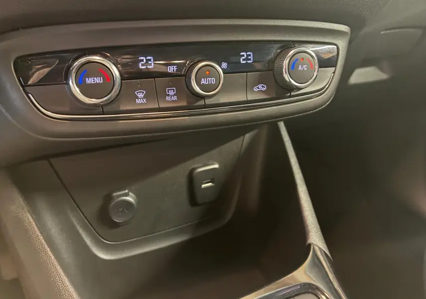Vue rapprochée de la commande de climatisation digitale et des prises USB et 12V de l’Opel Crossland gris 2021.