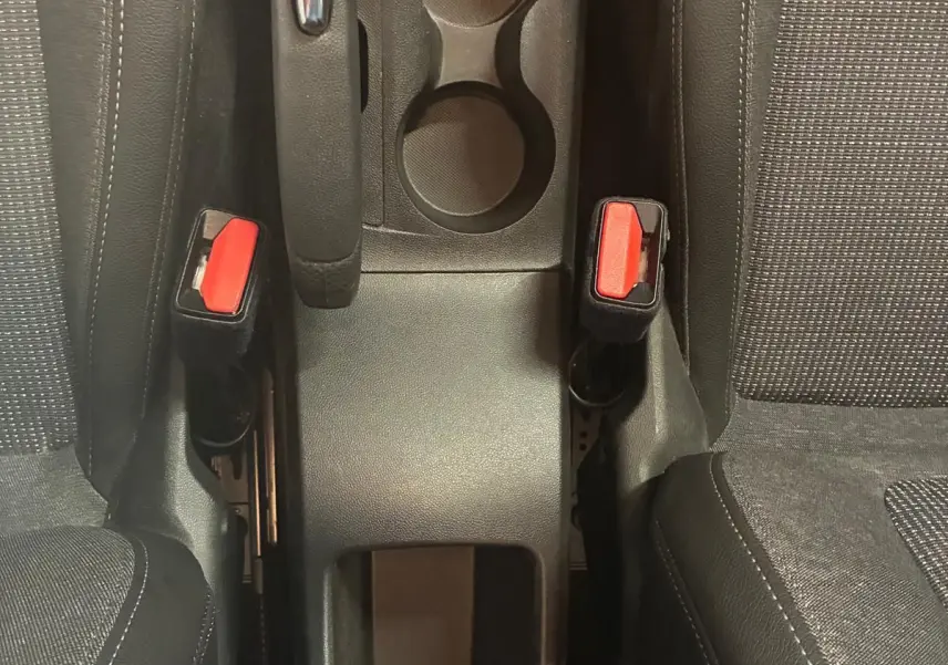 Vue plongeante sur la console centrale grise de l'Opel Crossland 2021, avec frein à main et porte-gobelets entre sièges tissu gris-noir.