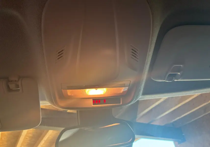 Plafonnier intérieur allumé avec miroir de courtoisie et pare-soleil dans un Opel Crossland gris, vue de l'habitacle vers l'avant.