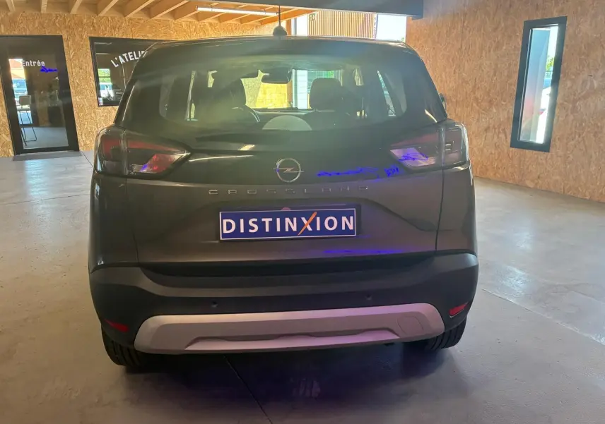 Vue arrière d'un Opel Crossland gris 2021 stationné en intérieur avec plaque Distinxion visible.