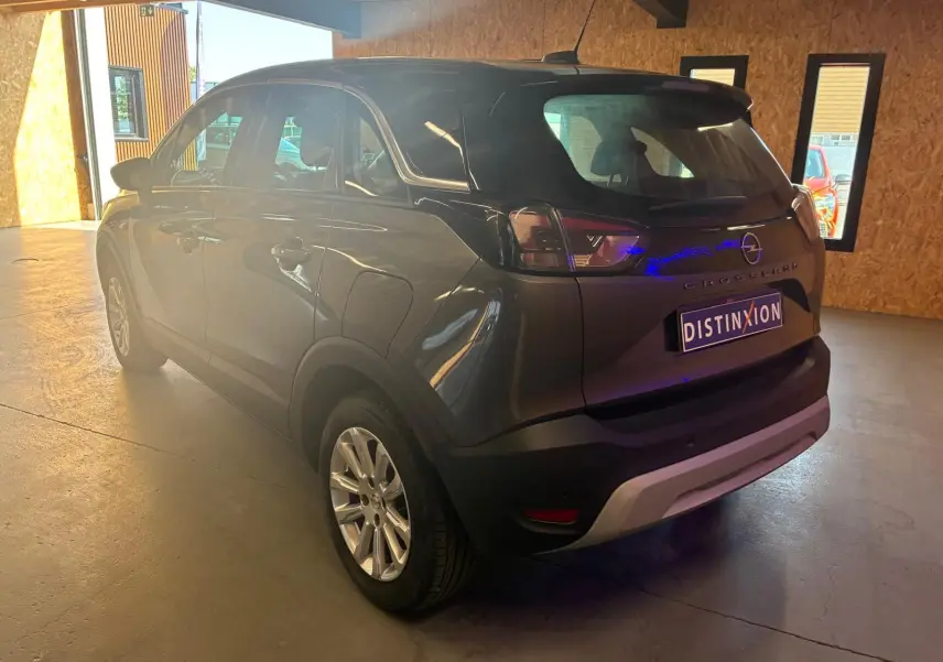Vue 3/4 arrière droite d'un Opel Crossland gris 2021 avec feux arrière LED et jantes alliage en intérieur lumineux.