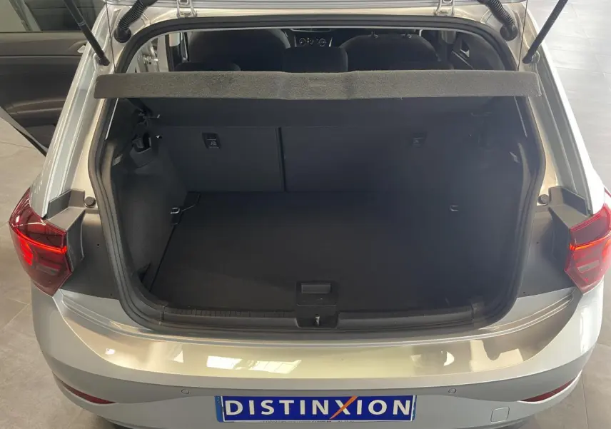 Vue arrière ouverte sur le coffre spacieux d'une Volkswagen Polo gris clair 2024 avec feux arrière allumés.