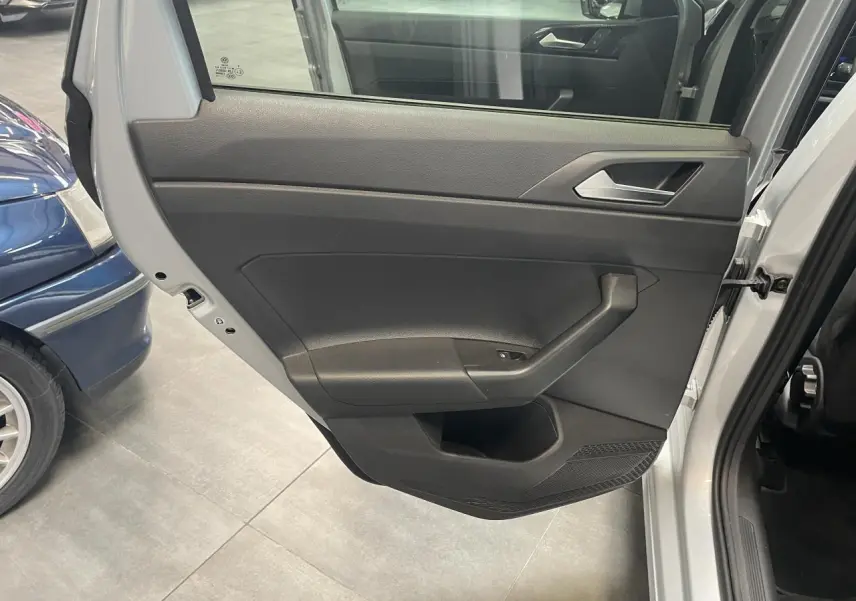 Vue rapprochée de la porte arrière droite gris clair de la Volkswagen Polo 2024, avec poignée intérieure et commande de vitre.