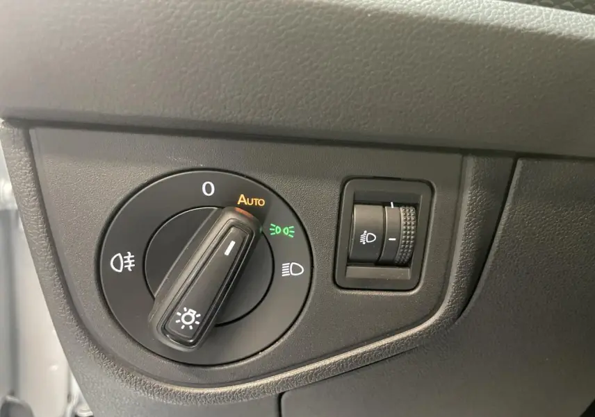 Gros plan sur le bouton de commande des phares d’un Volkswagen Polo gris clair, intérieur côté conducteur.