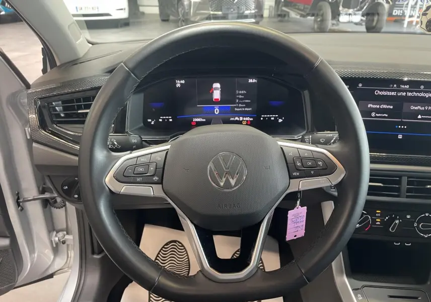 Vue intérieure centrée sur le volant cuir multifonction d'une Volkswagen Polo gris clair 2024 avec tableau de bord numérique.