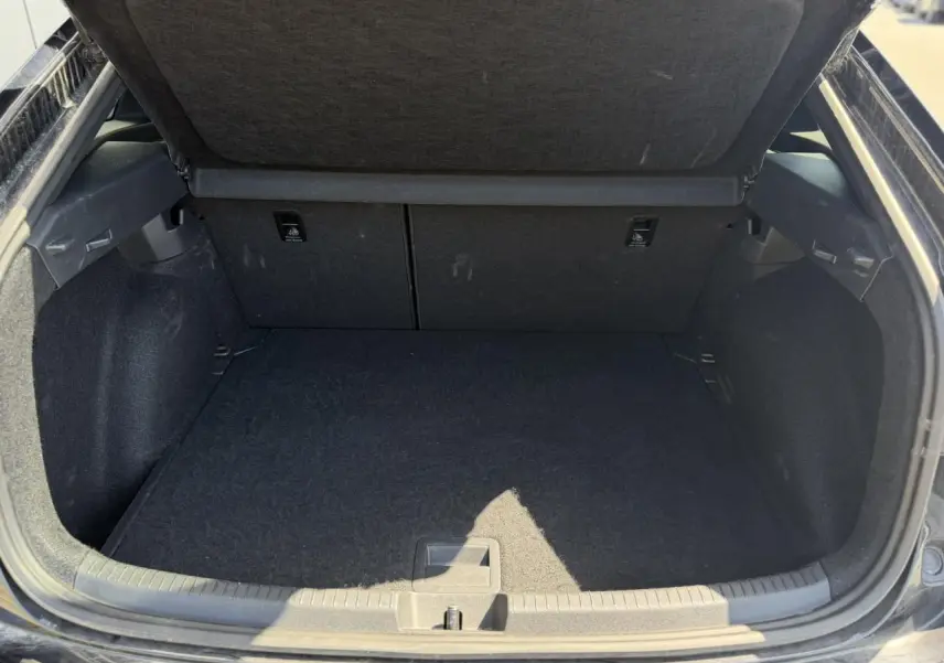 Coffre ouvert noir du Volkswagen Taigo TSI 116 DSG R-Line 2025, montrant l'espace de chargement vide et doublure noire.