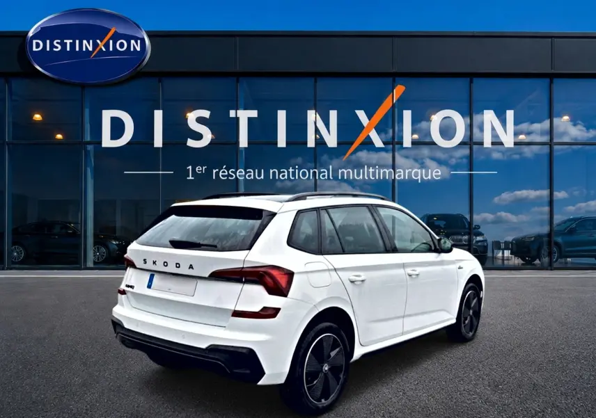 SKODA KAMIQ blanc nacré vu en 3/4 arrière droit devant un showroom Distinxion.