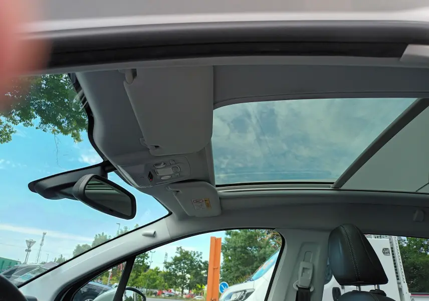 Vue intérieure du toit ouvrant panoramique et siège avant droit en cuir noir d'un Peugeot 2008 blanc 2018.