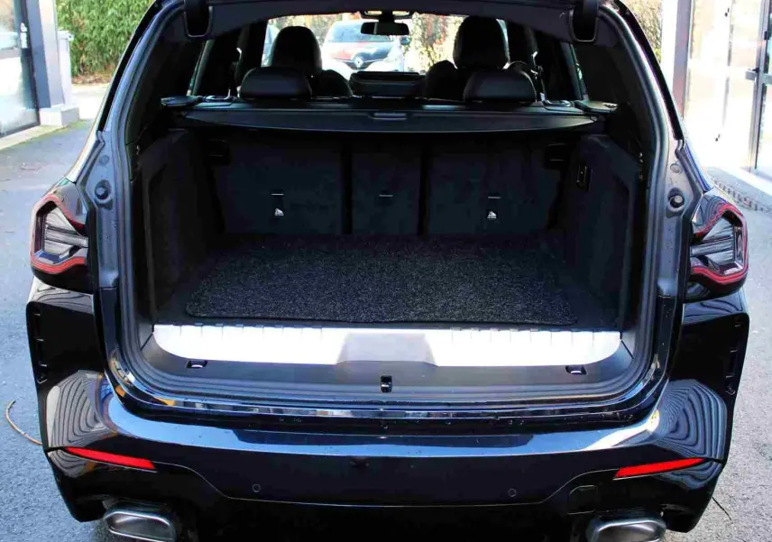 Coffre ouvert vu de l'arrière d'un BMW X3 xDrive bleu métal 2023, avec banquette arrière et feux LED visibles.