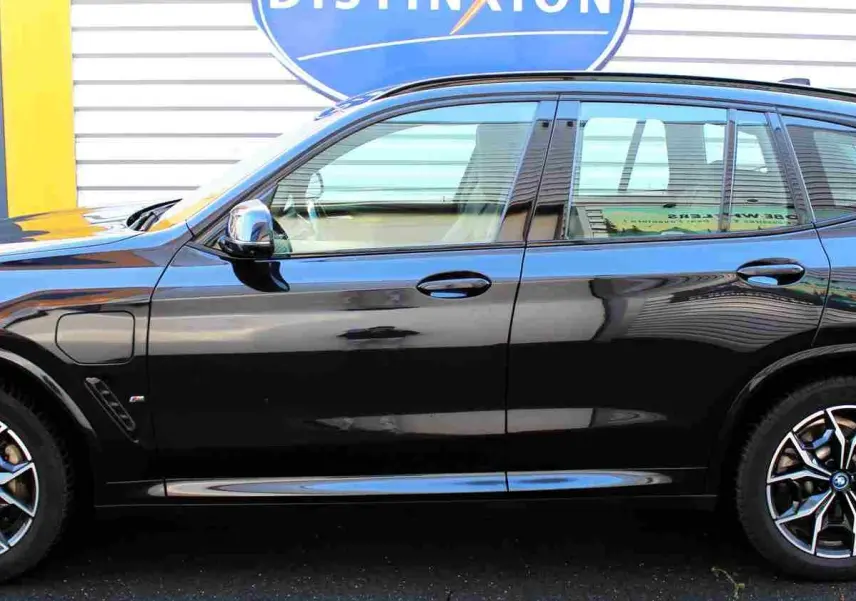Profil côté gauche d'un BMW X3 xDrive 30e 2023 en bleu métal avec jantes alliage et badge M Sport visible.