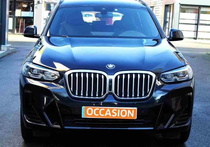 Vue frontale d'un BMW X3 xDrive bleu métal 2023 avec calandre imposante et plaque "OCCASION" orange.