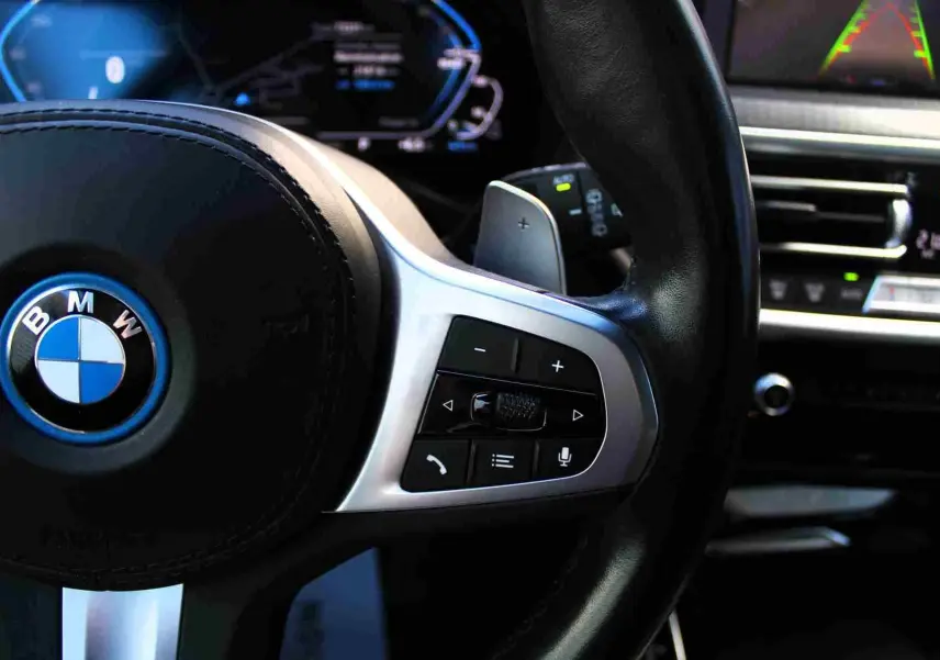 Gros plan sur le volant multifonction noir avec logo BMW bleu du BMW X3 xDrive 30e 2023 hybride rechargeable.
