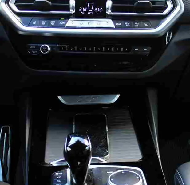 Vue intérieure centrée sur la console centrale et l'écran tactile du BMW X3 xDrive bleu métal 2023 hybride rechargeable.