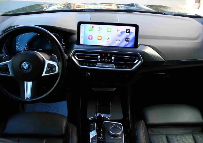 Vue intérieure frontale du tableau de bord du BMW X3 xDrive 30e 2023 avec écran tactile et volant M Sport noir.