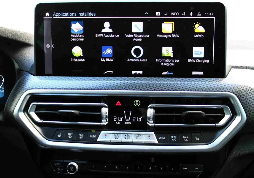 Vue rapprochée de la console centrale du BMW X3 xDrive 30e 2023, écran tactile et commandes climatisation visibles.