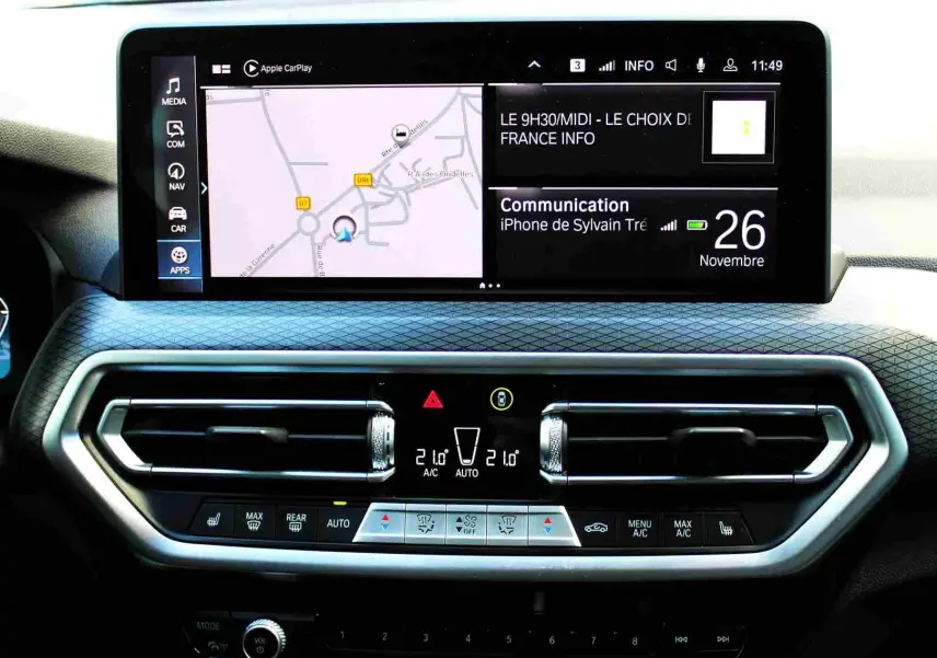 Tableau de bord BMW X3 xDrive 30e 2023 avec écran tactile et commandes climatisation en vue frontale rapprochée.