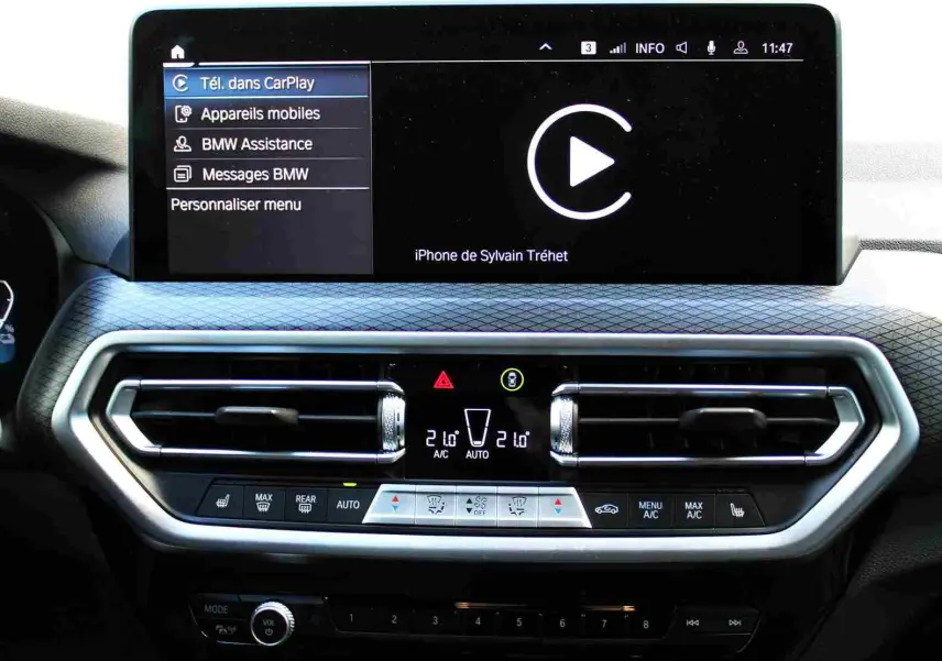 Tableau de bord du BMW X3 xDrive 30e 2023 avec écran tactile affichant CarPlay et commandes climatisation digitales.