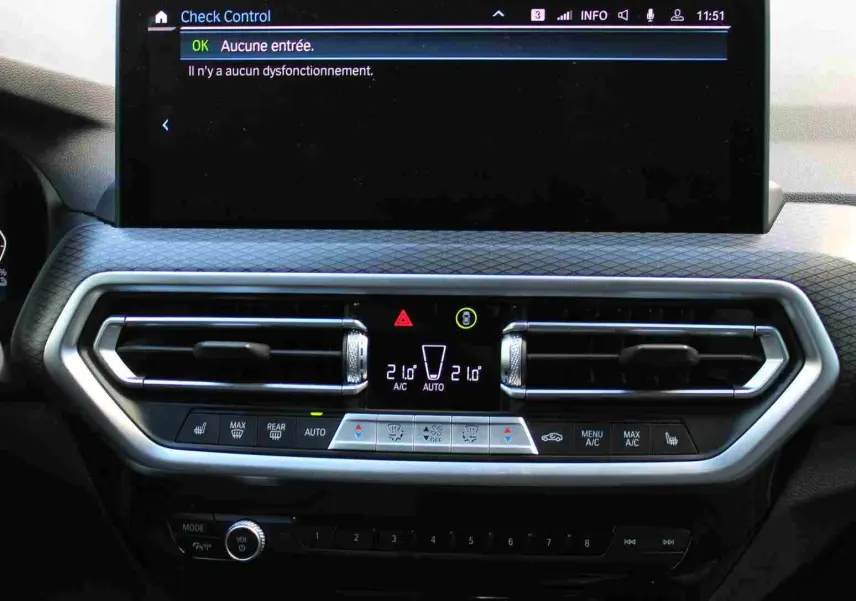 Vue rapprochée du tableau de bord du BMW X3 xDrive 30e 2023 bleu métal, affichant l'écran central et commandes climatisation.