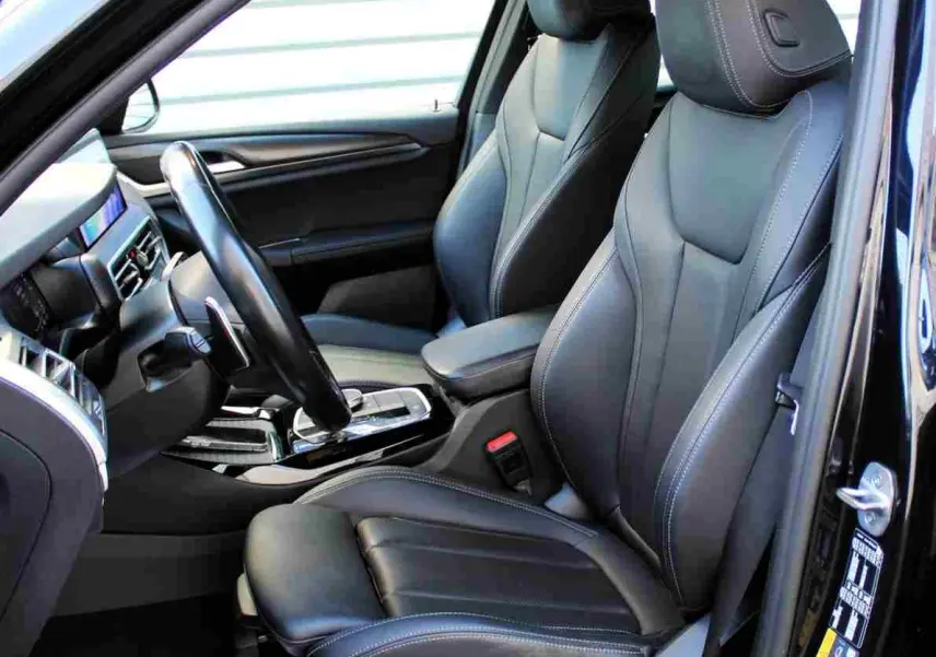 Vue intérieure côté conducteur du BMW X3 xDrive 30e 2023, sièges sport en cuir noir avec surpiqûres contrastées.