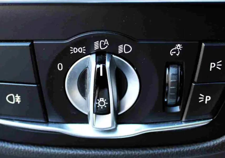 Commande des feux avec molette argentée et boutons noirs dans l'habitacle du BMW X3 xDrive bleu métal 2023