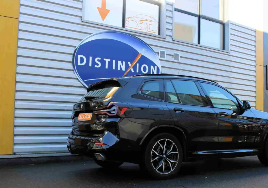 Vue 3/4 arrière d'un BMW X3 xDrive bleu métal 2023 avec jantes sport et badge hybride rechargeable visible.