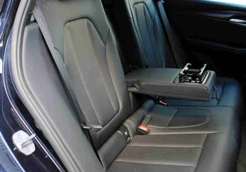 Vue intérieure côté gauche des sièges arrière en cuir noir avec accoudoir central déplié du BMW X3 xDrive 30e 2023.