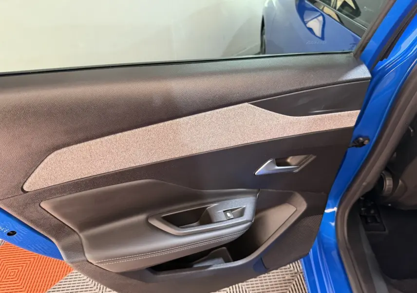 Vue rapprochée de la porte avant gauche bleu vif de la Peugeot 308 2023, avec garniture intérieure noire et beige.