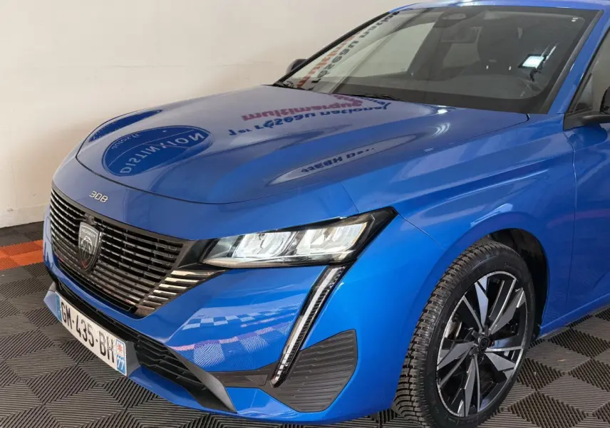 Vue 3/4 avant droit d'une Peugeot 308 2023 bleu électrique avec phares LED et jantes alliage distinctives.