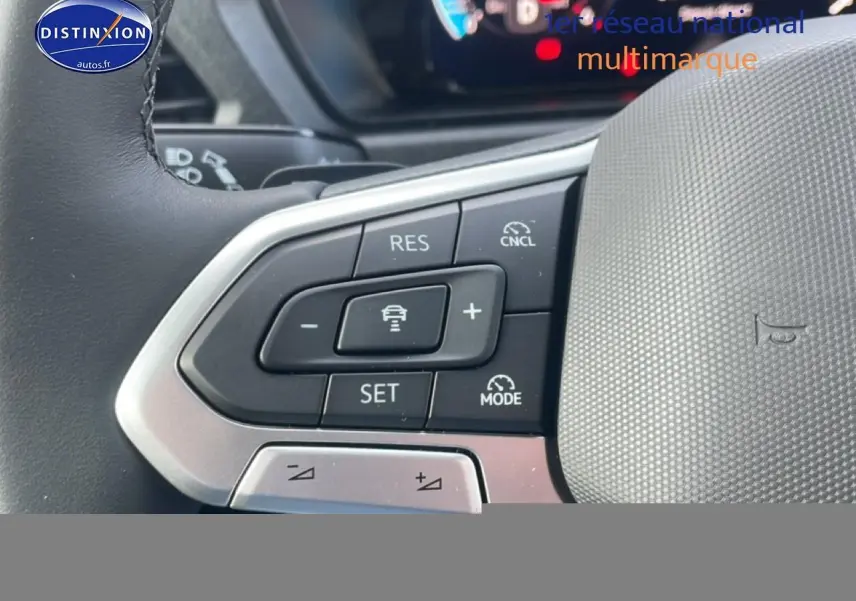 Gros plan sur les commandes au volant cuir multifonction du Volkswagen Caddy gris argent, mettant en valeur les boutons d'assistance à la conduite.