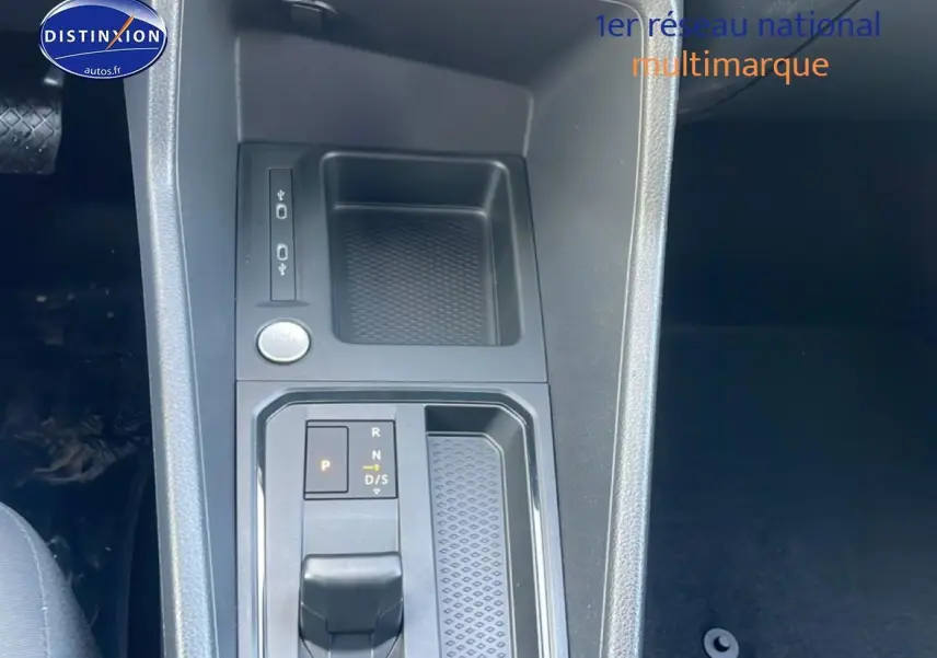 Gros plan sur la console centrale du Volkswagen Caddy gris argent, mettant en valeur le levier de vitesse automatique et le bouton start/stop.